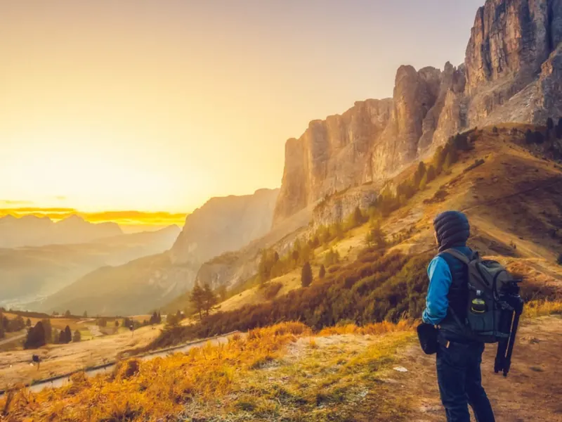 Hiker at sunset in front of the Dolomite rock walls