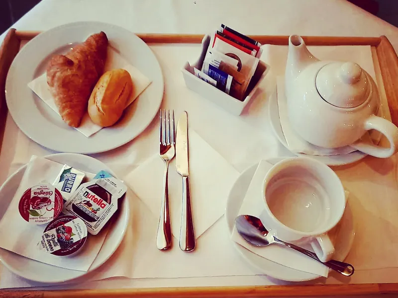 Breakfast tray with croissants, a teapot and jams