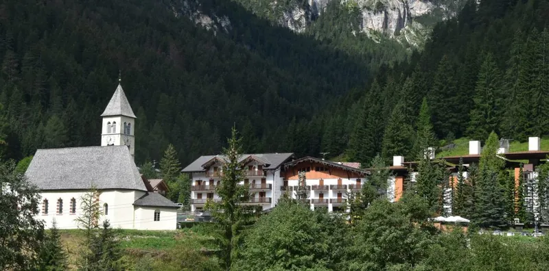The church of Mazzin and the village houses under the Dolomites